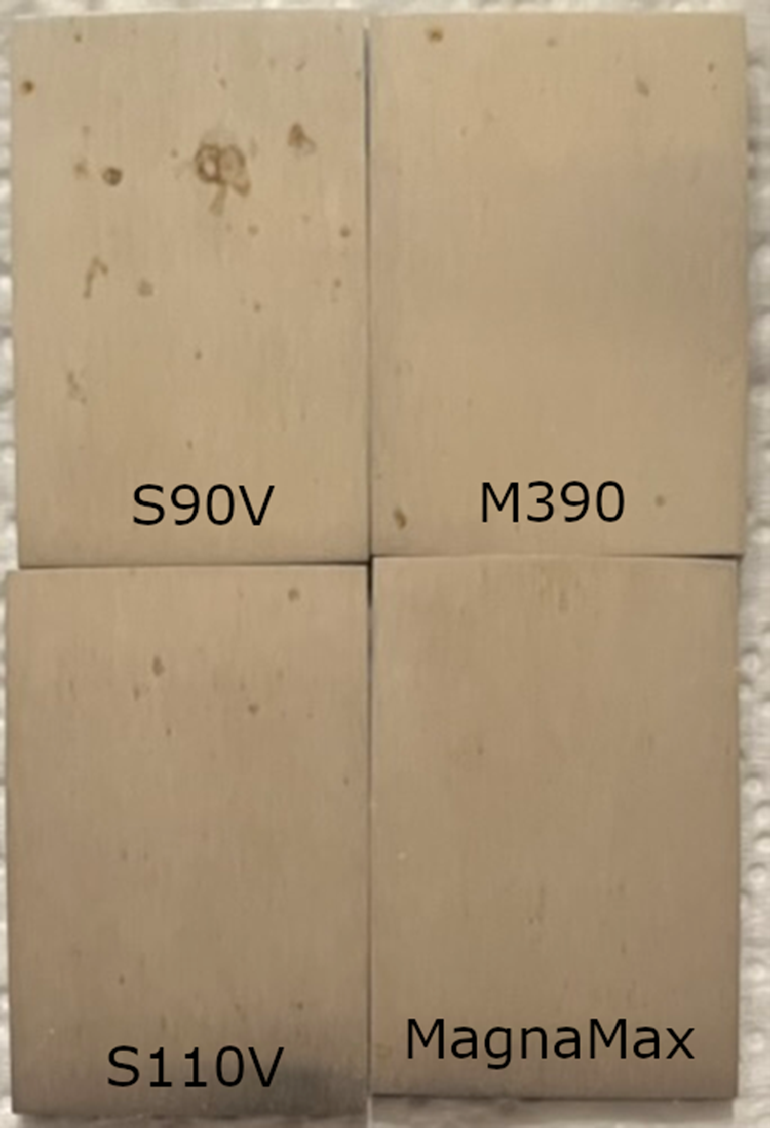 Corrosion resistance comparison after 1% saltwater exposure showing MagnaMax, S90V, S110V, and M390, with MagnaMax displaying no visible rust spots.