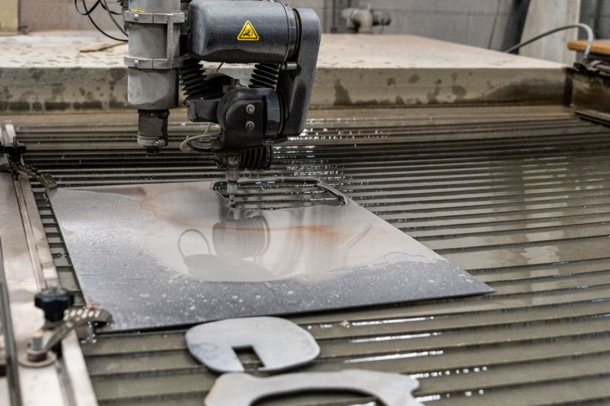 Water jet machine cutting high-performance powder metallurgy knife steel sheet at Niagara Specialty Metals for premium knife blade production.