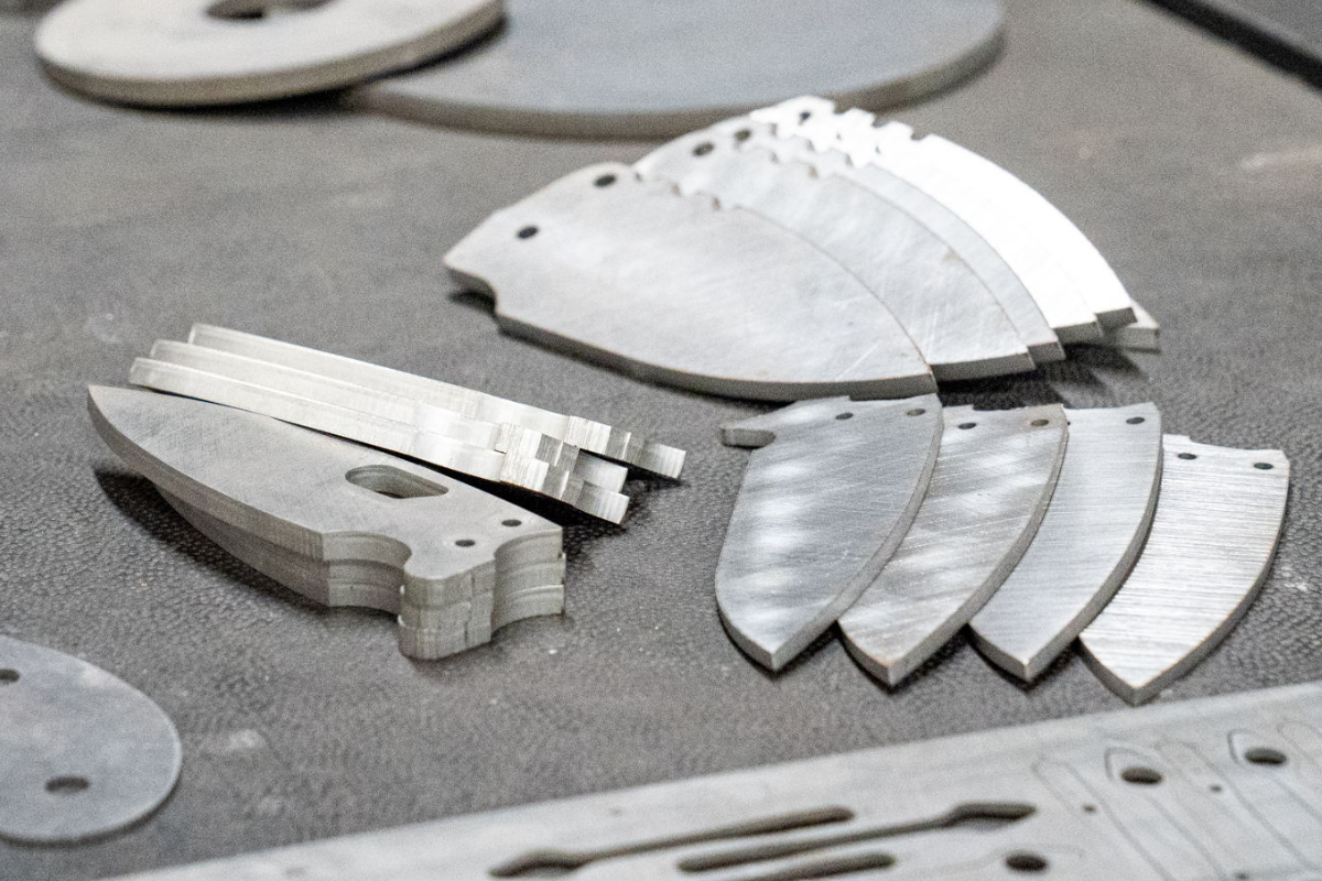 Cut out knife blades made from CPM® MagnaCut steel at Niagara Specialty Metals, showcasing high-performance stainless knife steel processing.