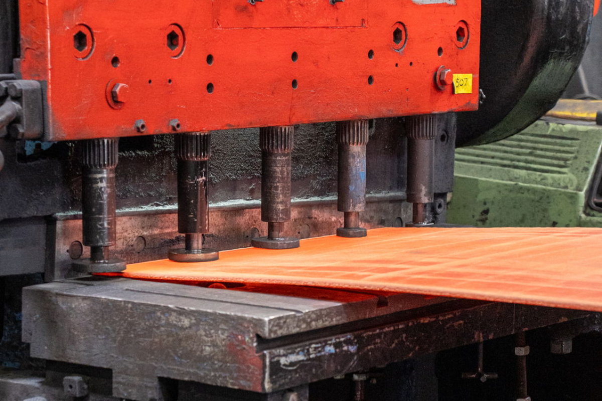 Specialty steel sheet moving through the shear in the plate mill at Niagara Specialty Metals for high-performance aerospace steel processing and manufacturing.